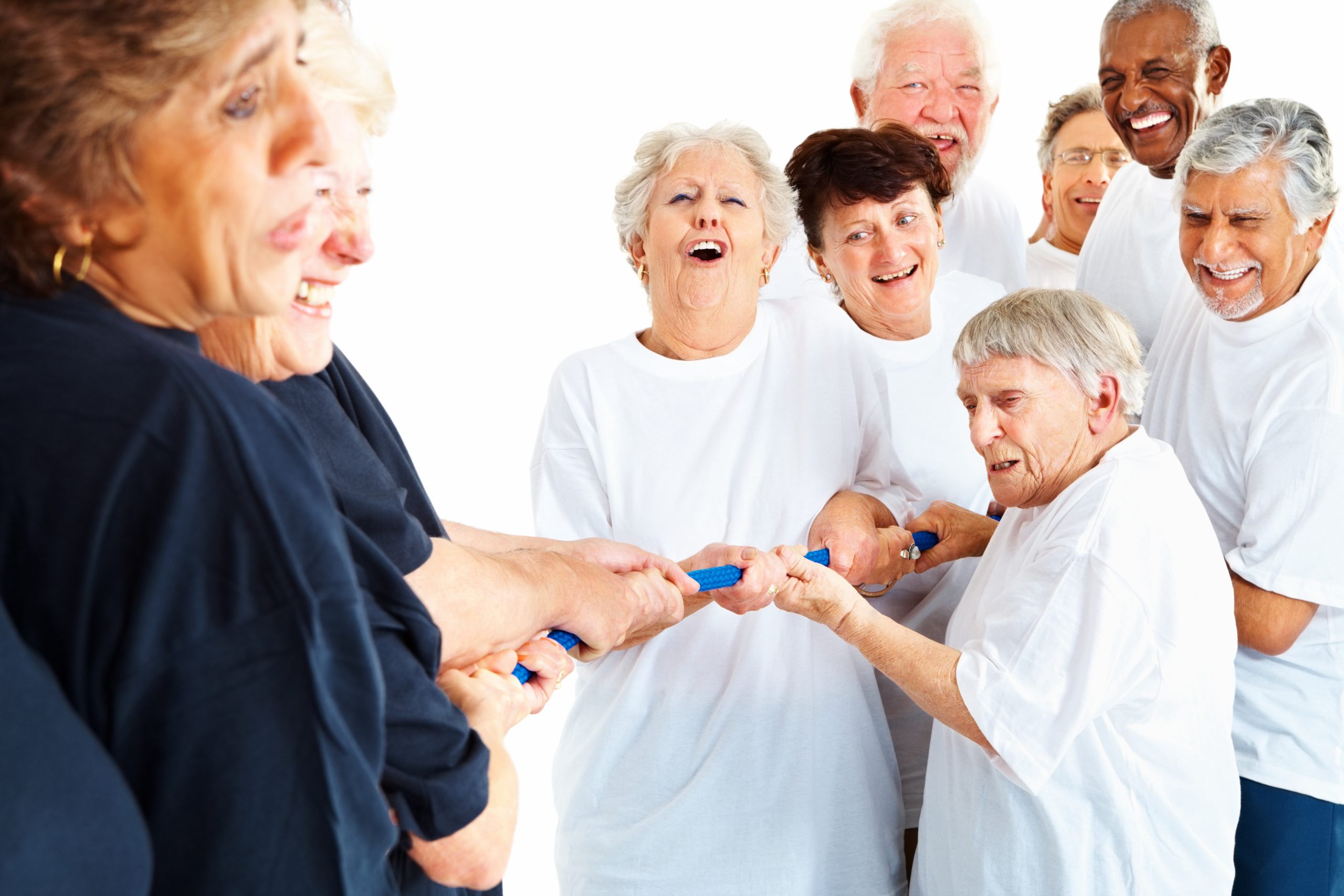 Ältere Menschen lachen beim gemeinsamen Tauziehen