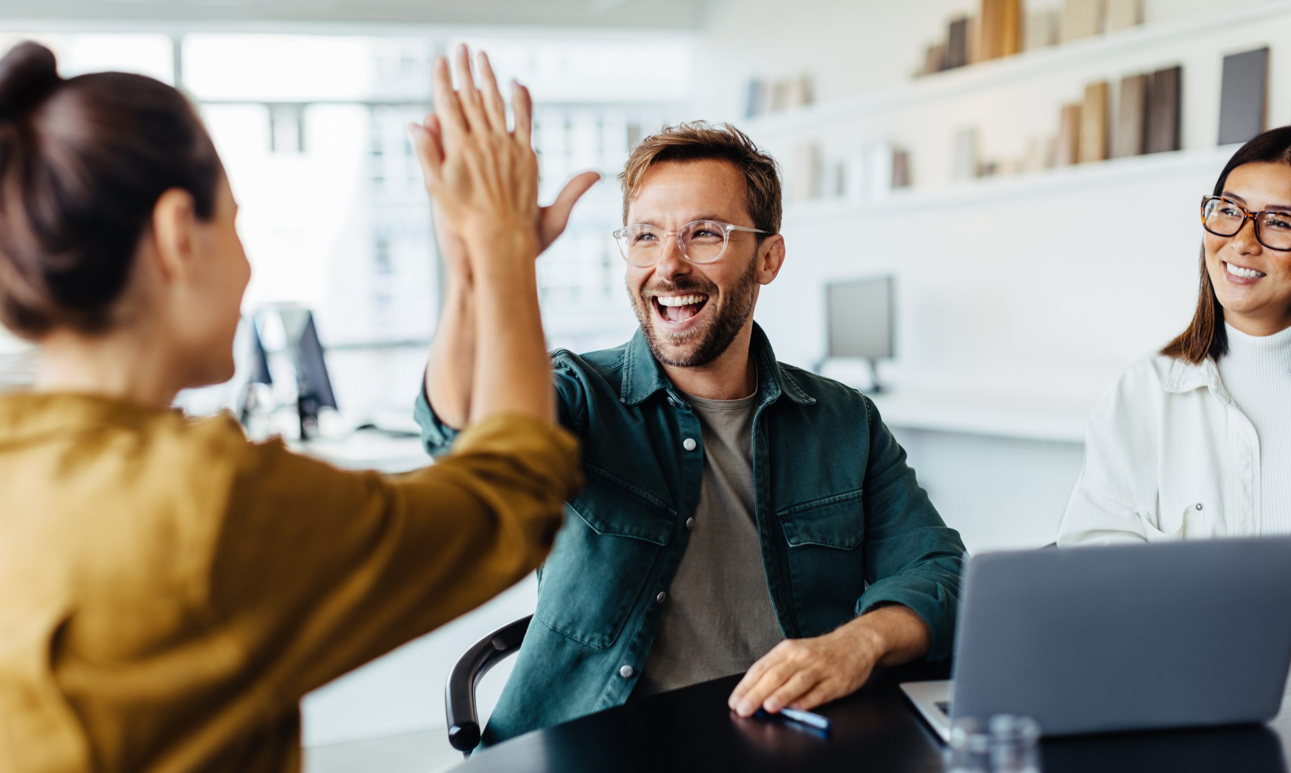 Kolleginnen und ein Kollege freuen sich gemeinsam im Büro